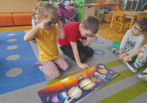 Dzieci oglądają planety przez okulary 3D.