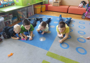 Dzieci dmuchają na piórka przez słomki.