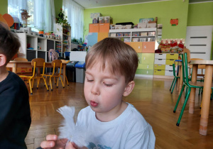 Chłopiec dmucha na piórko.