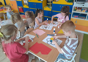 Dzieci wyklejają papierem kolorowym kwiat.