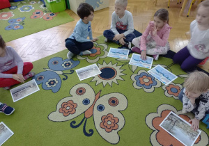 Dzieci oglądają dzieła malarstwa o tematyce zimowej.