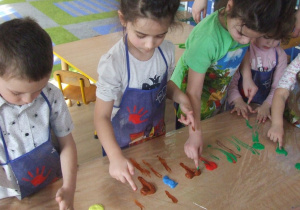 Dzieci malują palcami na folii.