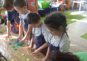 Dzieci malują palcami na folii.