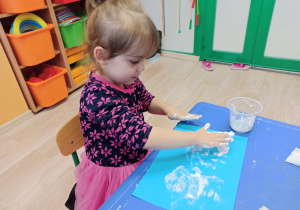 Dziewczynka maluje rękoma.