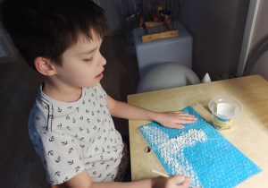Chłopiec maluje po foli bąbelkowej zimowy obrazek