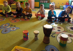 Dzieci grają na bębenkach wykonanych z puszek.