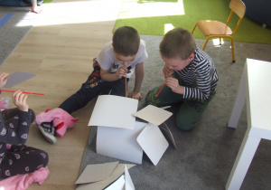 Dzieci dmuchają na domek z papieru.