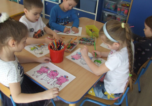Dzieci kolorują ilustrację trzech świnek.