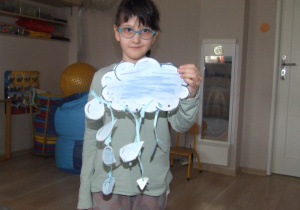 Dziewczynka prezentuje swoją pracę - chmura i deszcz.