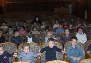 Dzieci siedzą w teatrze i czekają na przedstawienie.