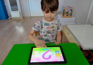 Dziecko pisze cyfrę 2 na tablecie