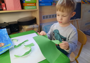 Chłopiec drze zielony papier.