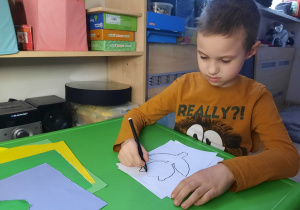 Chłopiec rysuje po śladzie tulipana.