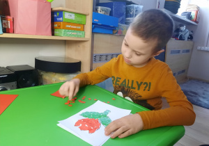 Chłopiec ozdabia papierem kolorowym tulipana.