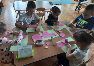 Dzieci wykonują świnki przy stoliku.