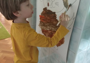 Chłopiec maluje duży obrazek.