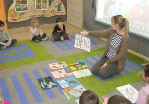 Nauczycielka pokazuje karty wykonane przez dzieci.