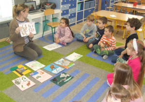 Nauczycielka pokazuje karty wykonane przez dzieci.