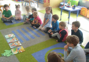 Dzieci słuchają opowiadania i oglądają ilustracje.