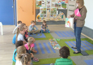 Dzieci słuchają opowiadania i oglądają ilustracje.