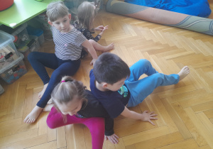 Dzieci w parach próbują wstać z podłogi.