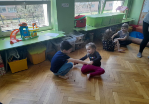 Dzieci w parach próbują wstać z podłogi.