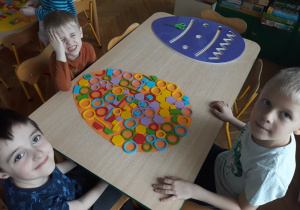 Dzieci układają wzór pisanki z klocków geometrycznych.