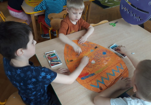 Dzieci malują dużą pisankę.
