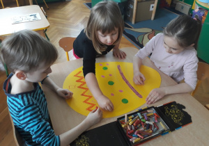 Dzieci malują dużą pisankę.