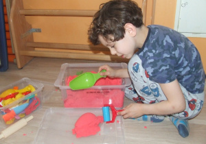 Chłopiec bawi się piaskiem kinetycznym.