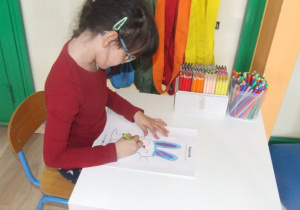 Dziewczynka rysuje drugą połowę obrazka.