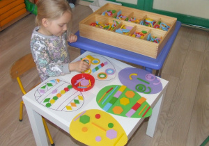 Dziewczynka układa wzory na szablonach jajek z klocków