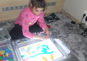 Dziewczynka układa wzory na panelu świetlnym.