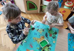 dzieci maluja rolki papieru na zielono.