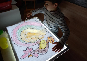 Chłopiec maluje na panelu świetlnym.