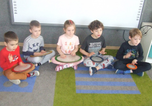 Dzieci grają na płaskich bębenkach.