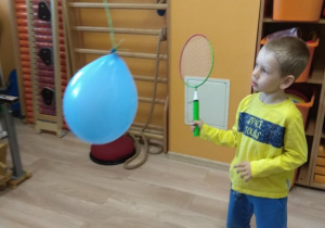 Chłopiec odbija rakietką balon.
