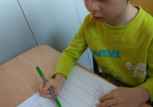 Chłopiec rysuje szlaczki.