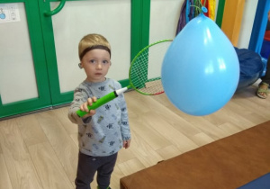 Chłopiec odbija rakietką balon.