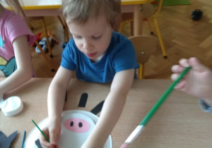 Chłopiec maluje krówkę.
