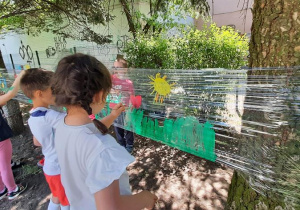 Dzieci malują na streczu kwiaty.