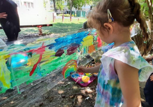 Dziewczynka maluje tęczę.