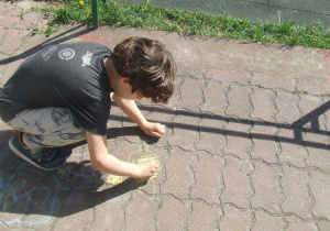 Chłopiec rysuje kredą na chodniku