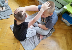 Chłopcy dotykają swoich głów.