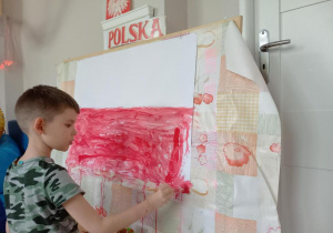 Chłopiec maluje flagę Polski.