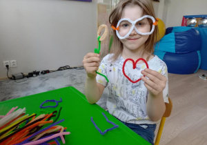 Dziewczynka pokazuje wykonane rzeczy z drucików kreatywnych.