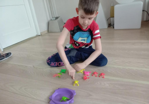 Chłopiec gra w grę z żabkami.
