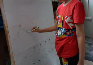 Chłopiec rysuje linie na planszy.