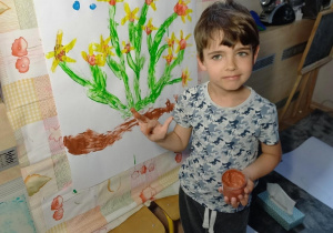 Chłopiec maluje kwiaty na planszy.