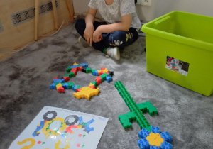 Chłopiec konstruuje wzory z klocków.